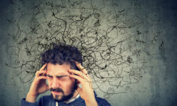 Young man holding his forehead while squiggles of worry and anxiety surround his head